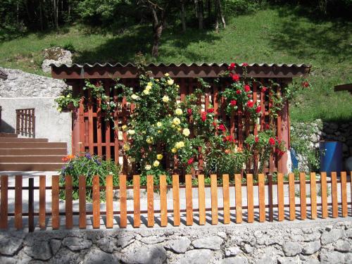 a wooden fence with flowers in front of a gazebo at Apartmaji in Sobe Cuder in Soča