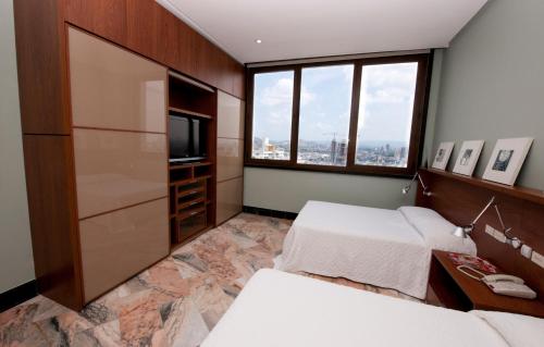 a hotel room with two beds and a television at Torres de Alba Hotel & Suites in Panama City