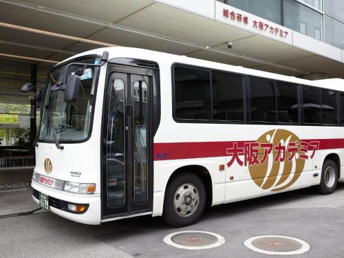 a white bus parked in front of a building at Osaka Academia in Osaka
