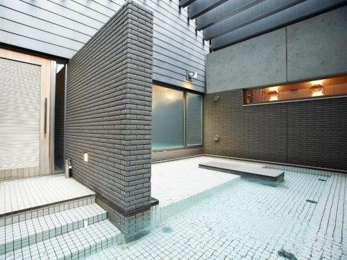 a room with a brick wall and a swimming pool at Osaka Academia in Osaka