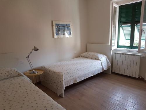ラ・スペツィアにあるSky Apartmentのベッドルーム1室(ベッド2台、ランプ、窓付)