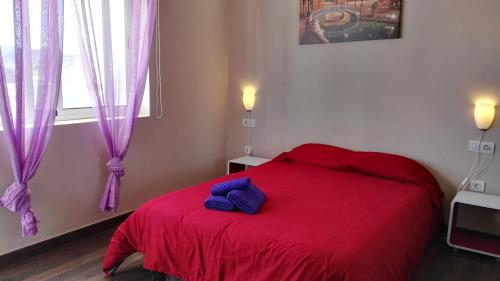 a bedroom with a red bed with purple sheets and a window at Atico La Laguna con terraza y vistas in Las Lagunas