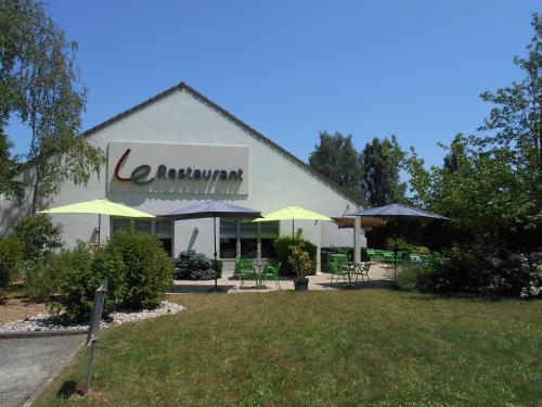a building with tables and umbrellas in a yard at Campanile Bourg-En-Bresse ~ Viriat in Viriat