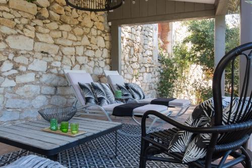 a patio with chairs and tables and a stone wall at Le Jardin d'Emile in Cassis