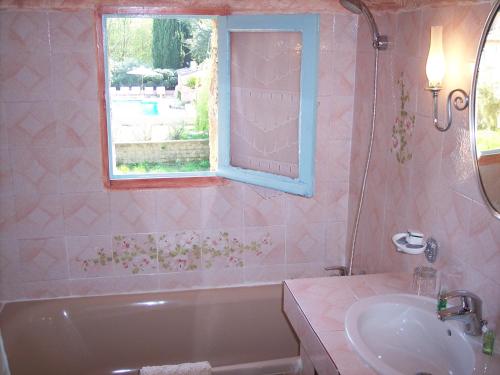 ein Bad mit einer Badewanne, einem Waschbecken und einem Fenster in der Unterkunft La Pierrerie in Grimaud