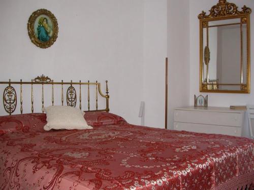 Schlafzimmer mit einem Bett mit einer roten Decke und einem Spiegel in der Unterkunft Casa del Ciliegio in Radicofani