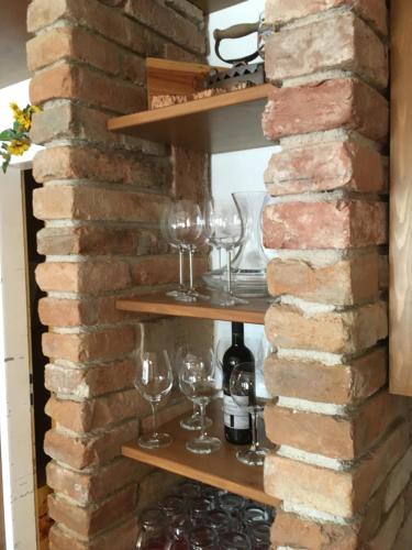 a brick wall with wine glasses on shelves at Andreashof Mörbisch in Mörbisch am See