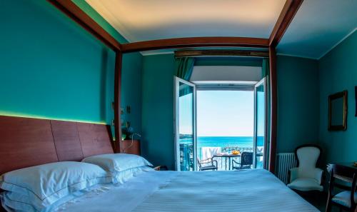 a bedroom with a bed and a view of the ocean at Hotel Palladio in Giardini Naxos