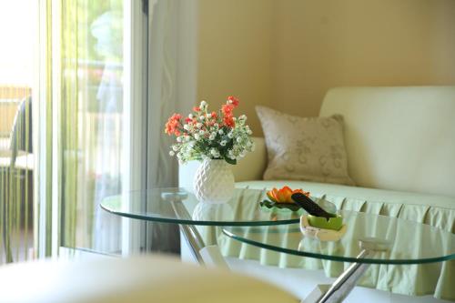 einen Glastisch mit einer Blumenvase darauf in der Unterkunft Apartments Lukic in Vrnjačka Banja