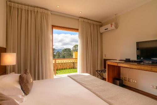 a hotel room with a bed and a large window at Hotel Le Renard - Campos do Jordao in Campos do Jordão
