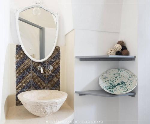 a bathroom with a mirror and a bowl on a shelf at Masseria Parco della Grava in Pezze di Greco
