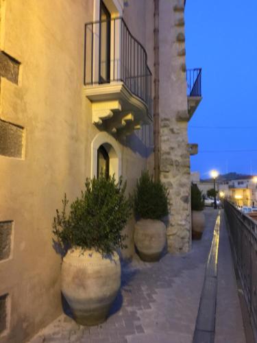 a building with large pots of plants on a sidewalk at B&B Santapau Charme Living in Licodia Eubea