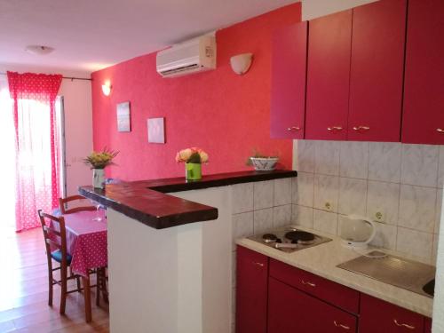 cocina con armarios rojos y encimera en Apartments Marija, en Stari Grad