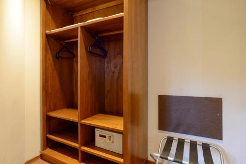 a room with a closet with a tv and a chair at Hotel Le Renard - Campos do Jordao in Campos do Jordão