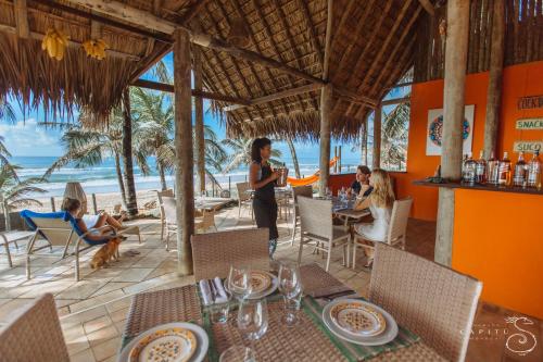 a woman standing in a restaurant on the beach at Pousada Capitù in Imbassai