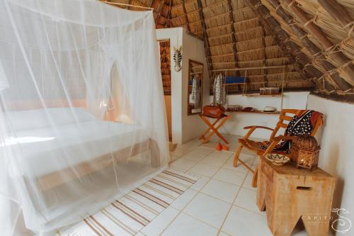 a bedroom with a bed with a mosquito net at Pousada Capitù in Imbassai