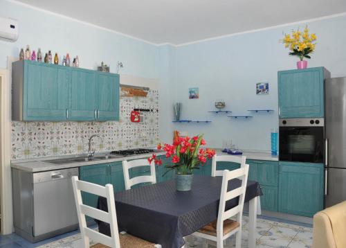 a kitchen with blue cabinets and a table with flowers on it at Villa Lery Guesthouse in Agropoli