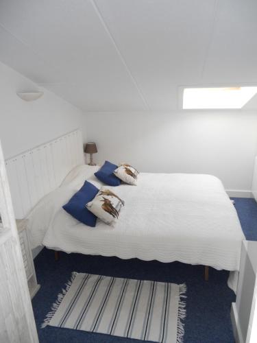 a white bed with blue pillows in a room at Duplex 6-7 p Résidence proche plage in La Couarde-sur-Mer