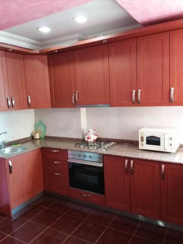a kitchen with wooden cabinets and a microwave at appartments in Batumi in Batumi