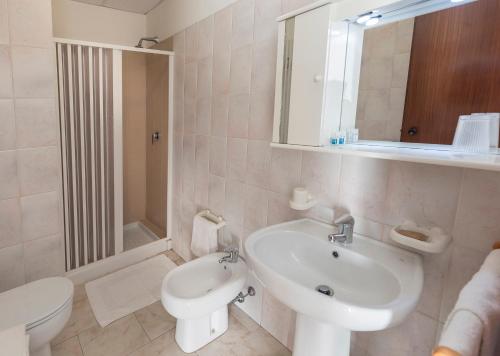 ein weißes Bad mit einem Waschbecken und einem WC in der Unterkunft Hotel Darsena in Passignano sul Trasimeno