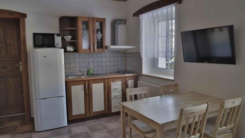 a kitchen with a table and a white refrigerator at Penzion Ostruznik in Ostružná