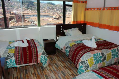 a bedroom with two beds and a large window at Hospedaje Qori Punku in Cusco