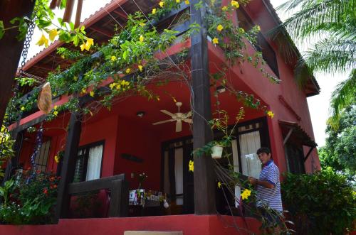 a man standing outside of a red house at Massai Apartments in Playa Flamingo
