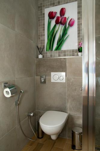a bathroom with a toilet and a picture of red tulips at Penzión Minipivovar Tatras in Poprad