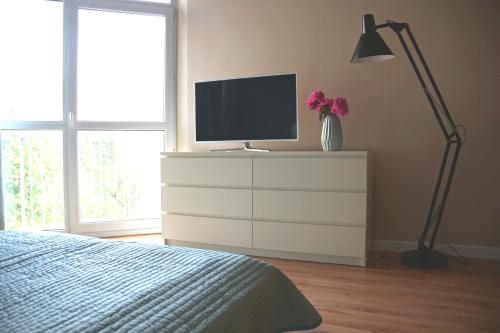 sypialnia z telewizorem na komodzie z łóżkiem w obiekcie APARTAMENT KOŁOBRZEG w Kołobrzegu