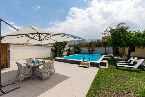 patio con tavolo, ombrellone e piscina di Vero Sicily - Villa San Giorgio a Cinisi