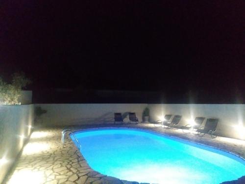 ein Pool mit Stühlen und Lampen in der Nacht in der Unterkunft Apartments T&C in Drage