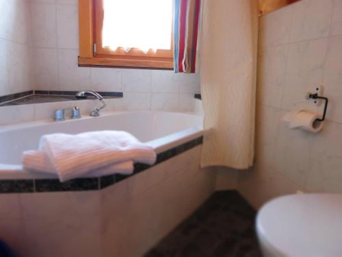 a bathroom with a tub and a toilet and a towel at Apartment-Foelslhof in Siegsdorf