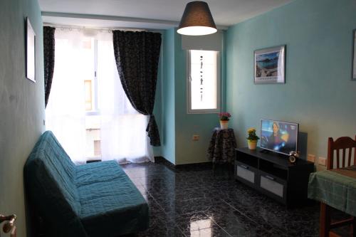 Una sala de estar con un sofá azul y un televisor. en el Bounty de Playa Chica, en Puerto del Rosario