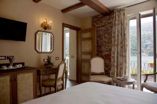 a bedroom with a bed and a desk and a window at Boutique Hotel Elvezia in Stresa