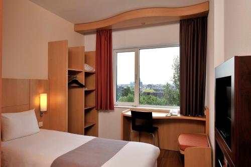a hotel room with a bed and a desk and a window at ibis Leiden Centre in Leiden