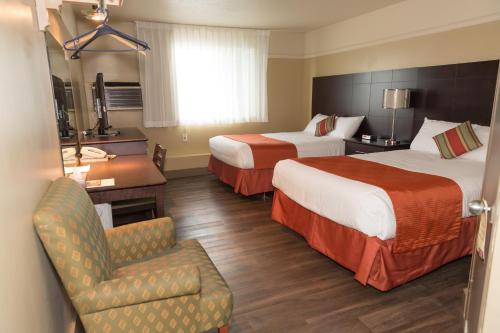 ein Hotelzimmer mit 2 Betten und einem Stuhl in der Unterkunft Hotel-Resto-Bar Le Journel in Saint-Joseph-de-Beauce