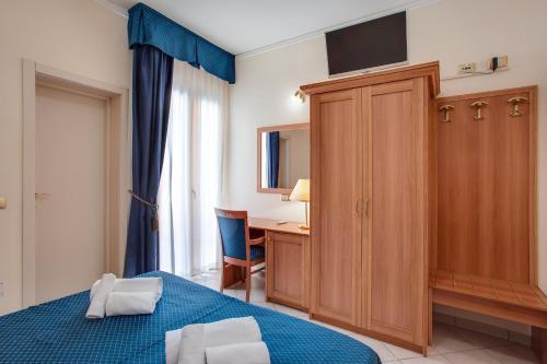 a bedroom with a bed and a desk and a cabinet at Hotel De La Ville in Cesenatico