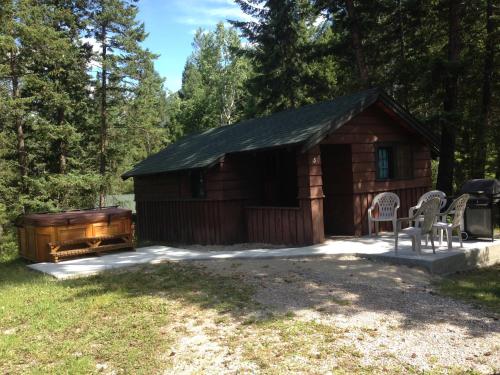 a log cabin with a grill and chairs in front of it at Addison's Bungalows in Brisco
