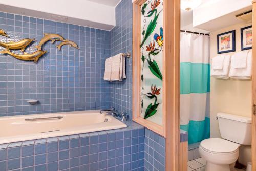 uma casa de banho com azulejos azuis, uma banheira e um WC. em Hawaiian Monarch Penthouse 402 em Honolulu