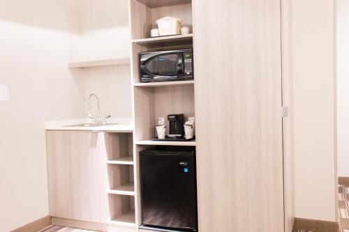 a kitchen with a black refrigerator and a microwave at Microtel Inn & Suites by Wyndham Springville in Springville