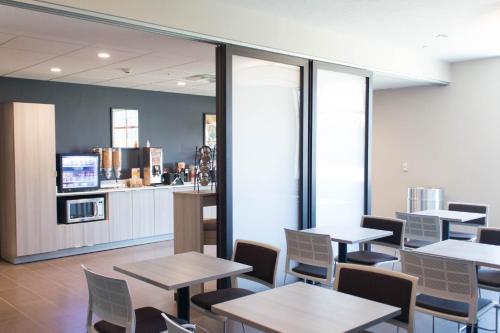 a restaurant with tables and chairs and a kitchen at Microtel Inn & Suites by Wyndham Springville in Springville