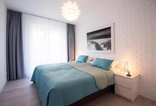 a bedroom with a bed and a chandelier at LATO apartament Solna 11c z garażem in Kołobrzeg