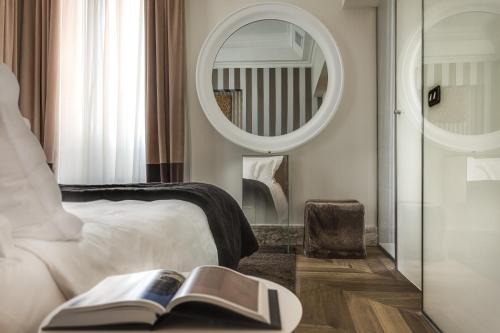 a bedroom with a bed with a book and a mirror at Hotel Palazzo Manfredi – Small Luxury Hotels of the World in Rome