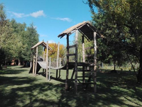 a wooden playground in a park with a tree at Establecimiento Rural El Chañar in San Rafael