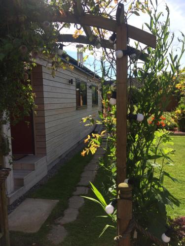a garden with a wooden pergola next to a house at The Wee Lodge in Inverness
