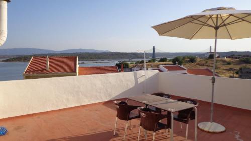 a patio with an umbrella and a table and chairs at Nunes Apartments in Mexilhoeira da Carregacao