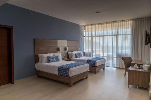 a bedroom with two beds and a large window at Ocean View Beach Hotel in Mazatlán