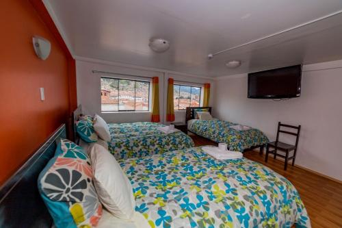 a bedroom with two beds and a flat screen tv at Hospedaje Qori Punku in Cusco