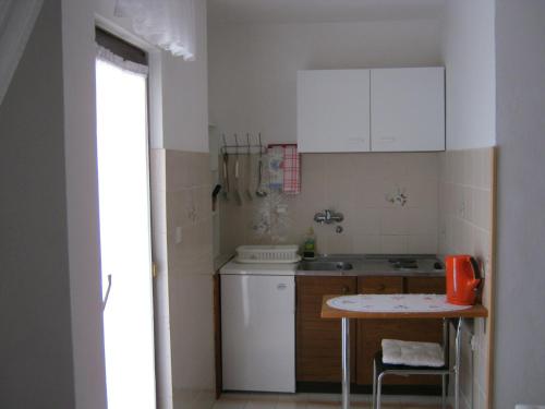 una pequeña cocina con armarios blancos y una mesa en Apartments Nestor, en Tribunj