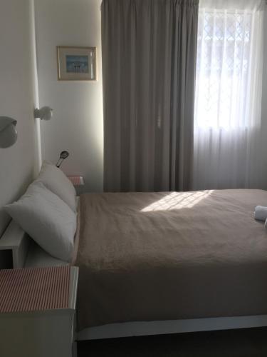 a bedroom with a large bed with a window at Merrima Court Holidays in Caloundra